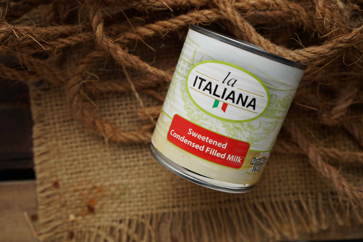 A can of La Italiana Sweetened Condensed Filled Milk resting on a rustic burlap surface wrapped in natural jute rope.
